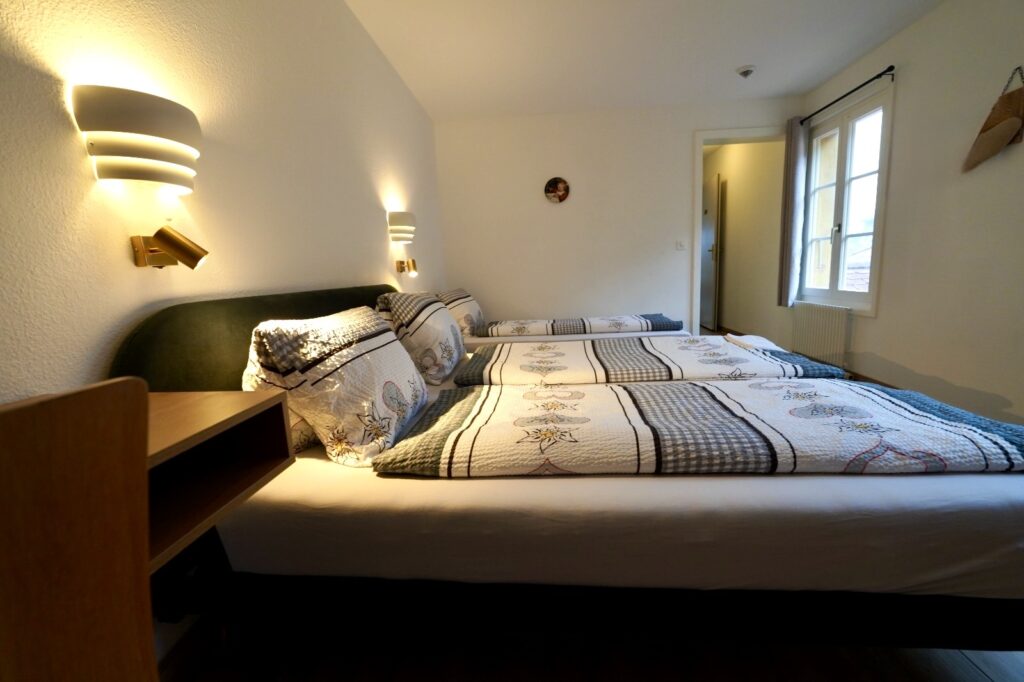 Bright family room with three prepared beds at Hotel Du Lac